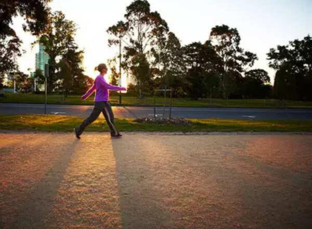 Person briskly walking in a park for cardiovascular exercise.